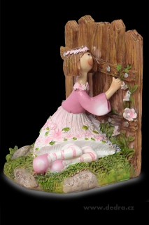 Květinová panenka z boku  držící se plotu
