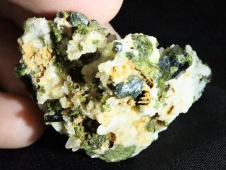 Bílý albit posetý krystalky a fragmenty zelenkavého epidotu