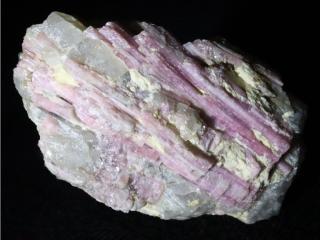Sloupcovité krystalky růžového turmalínu rubelitu zarostlé v křemeni